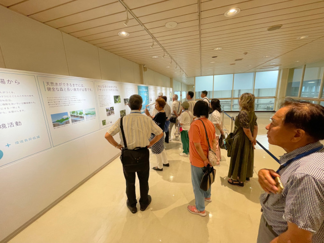サントリービール京都工場内部の見学コース。植林活動についてのパネル展示を見ている参加者たち
